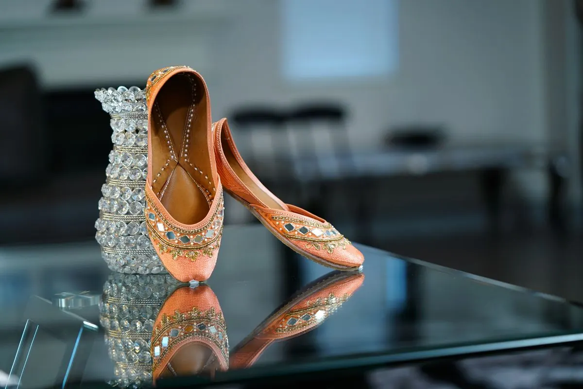 Delicate pink satin ballet shoes on a glass surface.