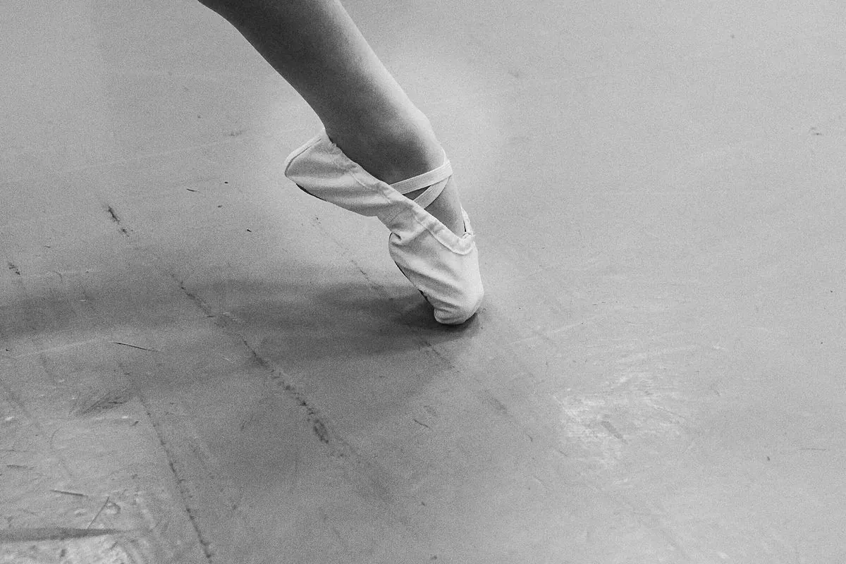 Artistic black-and-white study of a ballerina's pointe shoes in motion.
